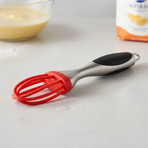 A close-up of a high-quality silicone-coated flat whisk with a comfortable, heat-resistant handle.